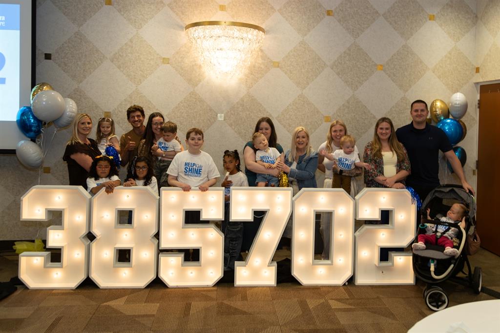 Large group standing behind large marquee numbers, 385,702